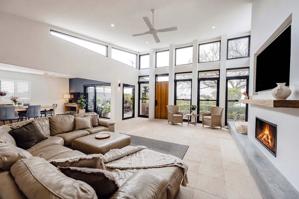 New lounge room with burnished concrete fireplace plinth and full-height windows
