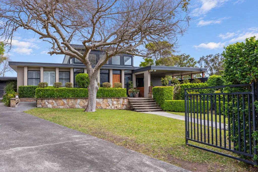 Renovated home behind a black steel gate and established gardens