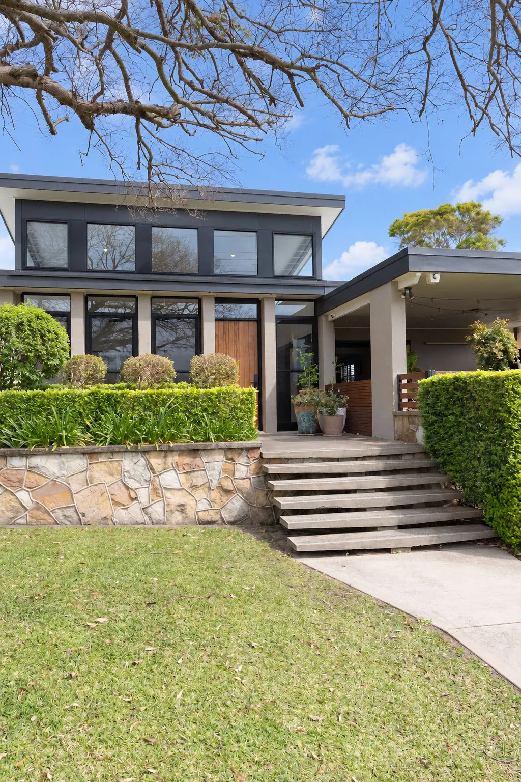 Stone retaining wall and steps up to the renovated home