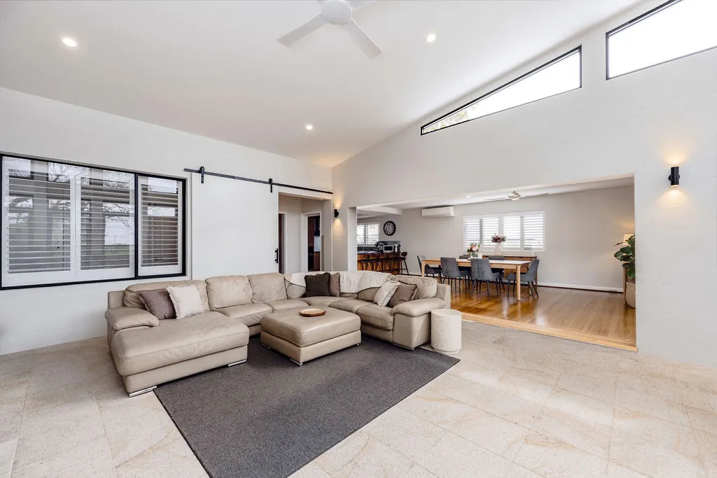 Light-filled lounge room with high windows and stone-look floor tiles